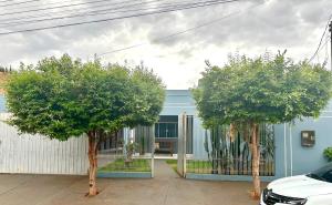 a blue house with two trees in front of it at Casa ampla e confortavel in Tangara da Serra