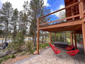 two red chairs and a grill on a patio at Sleeps 30, Riverfront, HotTub, PoolTable, DiscGolf in Three Rivers