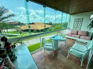 ein Balkon mit Tisch und Stühlen und einem großen Fenster in der Unterkunft Flat 601 Condominio Villa Hípica - Gravatá, PE in Gravatá