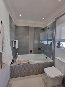 a bathroom with a bath tub and a toilet at Alice in Wonderland in Kimberley