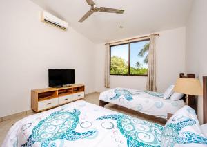 a bedroom with two beds and a tv and a window at Paradizio 301 in Coco +23 photos