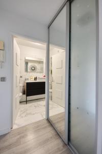 una puerta corredera de cristal que conduce a un baño con lavamanos en Beautiful modern fully furnished studio, en Levallois-Perret 11 fotos más