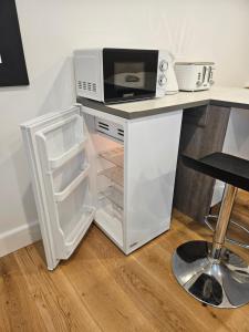 a white refrigerator with a microwave on top of it at The Annexe in Northam