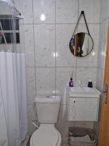 a bathroom with a toilet and a sink and a mirror at Casa 1 quarto 2 pessoas a 3 km da Oktoberfest in Blumenau