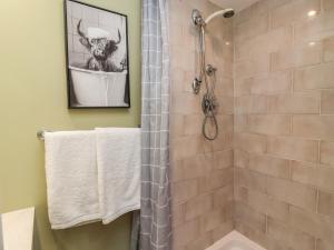 a bathroom with a shower with a cow in a bucket at Figgy Cottage in Ripon +12 photos