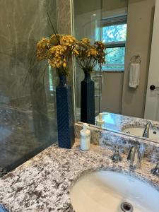 two blue vases with flowers on a bathroom sink at Vancouver West Shaughnessy Maison in Vancouver
