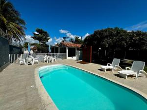 a swimming pool with white chairs at Casa em bairro nobre de Prado in Prado