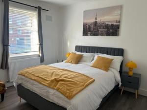 una camera da letto con un letto con lenzuola bianche e cuscini gialli di Eugino Properties a Stifford