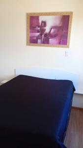 ein Schlafzimmer mit einem blauen Bett und einem Gemälde an der Wand in der Unterkunft Apartamento 01 dormitório, mobiliado, equipado in São Leopoldo