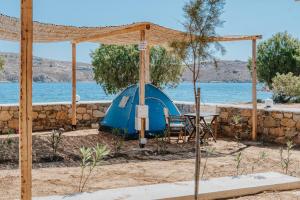 a blue tent with a table and chairs in front of the water at Coralli Camping in Livadakia