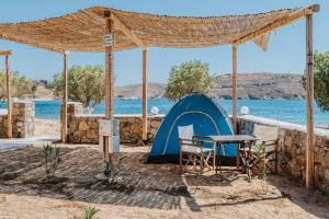 a tent and a table and chairs in front of the water at Coralli Camping in Livadakia