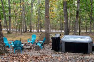 a hot tub and chairs in the woods at Dog-Friendly w Hot Tub, Fire Pit & River Access in Great Cacapon