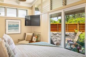 a bedroom with a bed and a flat screen tv at Ocean View Cottage Wlk To Poipu & Brenneckes Beach in Koloa