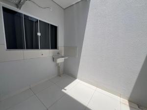 a white bathroom with a window and a white tile floor at Residencial jardim bougainville in Sinop +9 photos