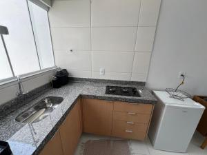 a small kitchen with a sink and a stove at Residencial jardim bougainville in Sinop