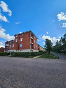 un bâtiment en briques rouges avec un ciel bleu en arrière-plan dans l'établissement Bargh Apartment - 2 bed 2 bath, modern comfort, à Balderton