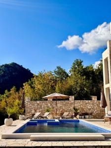 a swimming pool with chairs and an umbrella next to a building at Villa Lotos in Budva