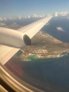 une vue sur l'aile d'un avion survolant l'océan dans l'établissement Apartahotel curacao, à Willemstad