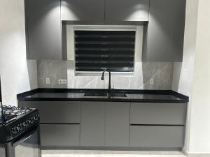 a kitchen with white cabinets and a sink and a window at JRMN Property - 5 minutes from Blue Bay beach, Boka Sami & Kokomo Beach in Dorp Sint Michiel