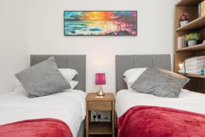 a bedroom with two beds and a painting on the wall at Franks house, 3 Bedroom in Liverpool - sleeps 5, Newly refurbished - long stays welcome, free parking in Litherland