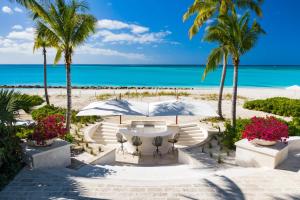 a patio with a table and palm trees on the beach at 7 bedroom plantation estate Villa in Leeward