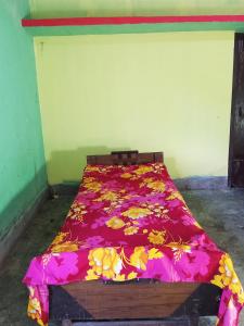 a bed with a red blanket with flowers on it at Jacobs Homestay Unit 1 Low Budget in North Lakhimpur