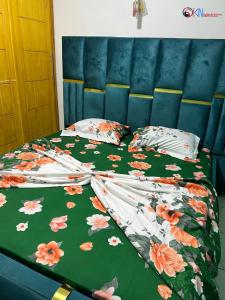 a bed with a floral comforter and pillows on it at IKN résidence in Douala +6 photos