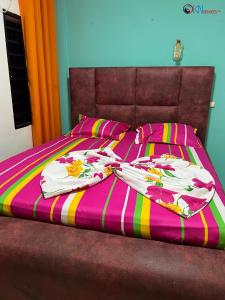 a bed with a pink and colorful blanket on it at IKN résidence in Douala