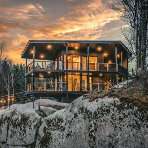 Una casa en lo alto de una roca con una puesta de sol. en Tricera - Panoramic View near Quebec City, en Lac-Beauport