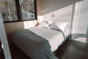 Una cama en una habitación pequeña con ventana. en Tricera - Panoramic View near Quebec City, en Lac-Beauport