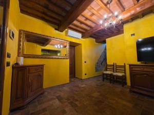 a living room with yellow walls and a flat screen tv at Villa Benedetti in Galleno