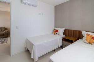 ein Zimmer mit zwei Betten und einem Stuhl in der Unterkunft 15 Andar, 2Q Suite Vista Mar, Ed Palmer, NOMDS in Insel Itaparica