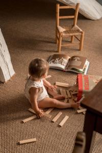 Una bambina seduta sul pavimento a leggere un libro di Hôtel Demeures de Campagne Domaine de Maffliers - Paris Val-d'Oise a Maffliers