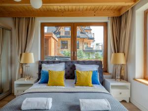 a bedroom with a bed with yellow and blue pillows at Osada Gubałówka na Polanie Pająkówka View Jacuzzi & Sauna in Kościelisko