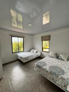 a bedroom with two beds and two windows at Entre Montañas in Vergara