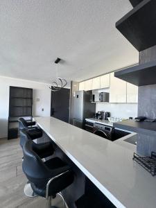 a kitchen with a large white counter with black appliances at Matías Plaza in Santiago