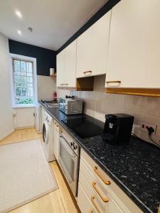 a kitchen with white cabinets and a black counter top at Diagon Alley two bed apartment Victoria street grassmarket in Edinburgh