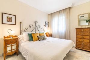 a bedroom with a large white bed and a dresser at Apartamento Costa Nagüeles 2hab. in Marbella