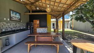 a patio with two tables and a table and benches at Casa Temporada Brisa do Mar in Guriri