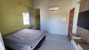 a bedroom with a bed and a flat screen tv at Casa Temporada Brisa do Mar in Guriri