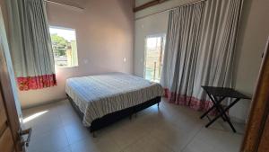 a bedroom with a bed and a table and windows at Casa Temporada Brisa do Mar in Guriri
