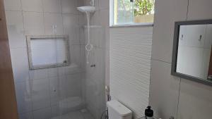 a bathroom with a shower with a toilet and a window at Casa Temporada Brisa do Mar in Guriri +30 photos