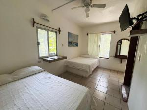 a bedroom with two beds and a tv and two windows at Hotel Cocoloco in Costa Esmeralda