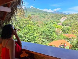 a woman sitting on a balcony looking out at the mountains at MAYU PATANPI Amazon Lodges in Tarapoto