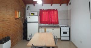 eine Küche mit Holztisch und Kühlschrank in der Unterkunft Cabañas La Petunia in Santa Rosa de Calamuchita