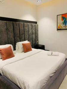 a bedroom with a large bed with white sheets and orange pillows at Alphavista Luxury Apartments in Port Harcourt
