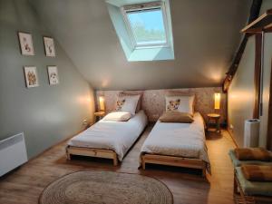 a attic bedroom with two beds and a skylight at Les logis de La Tribu in Jouaignes