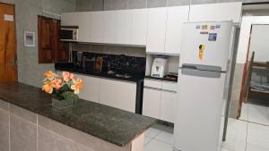 a kitchen with a white refrigerator and a vase of flowers at Enseadabechouse in Cabo de Santo Agostinho