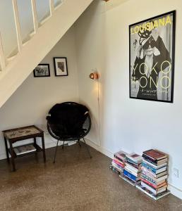 a room with a chair and a pile of books at Charming apartment by forest & beach on Tåsinge in Svendborg