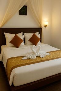 a bedroom with a bed with white sheets and pillows at EMERALD HAVEN SAFARI Cottages in Udawalawe